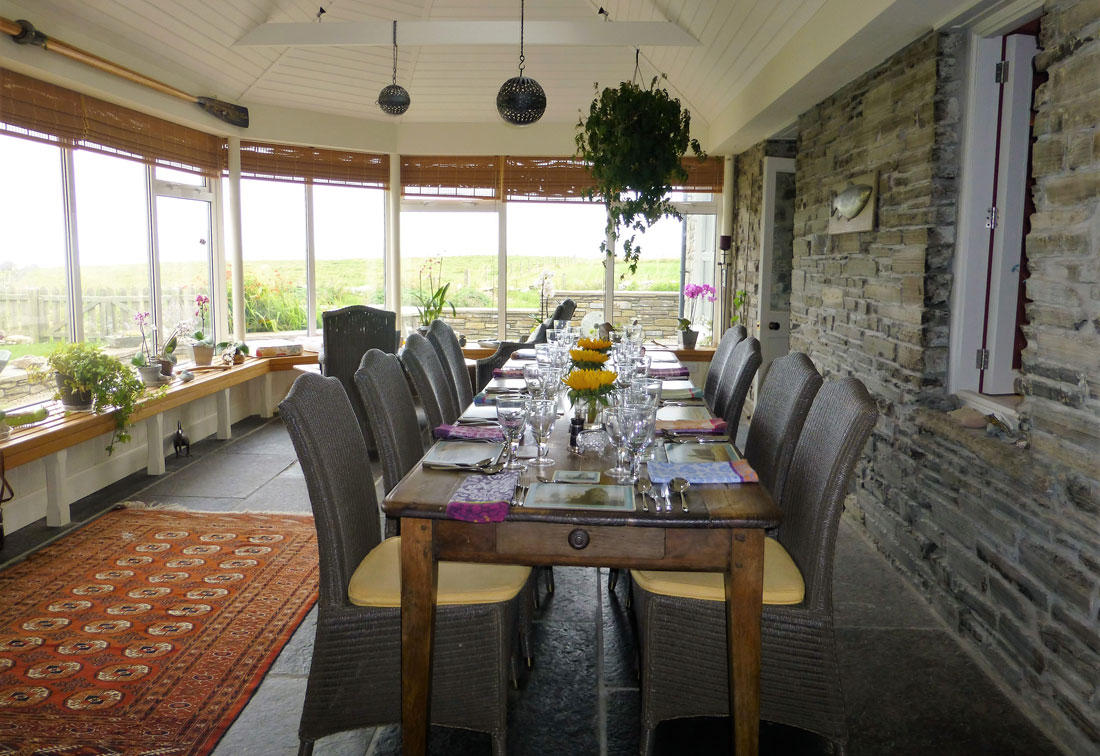 Dining room in a home in Orkney, Scotland with a long wooden table and plants hanging from the ceiling