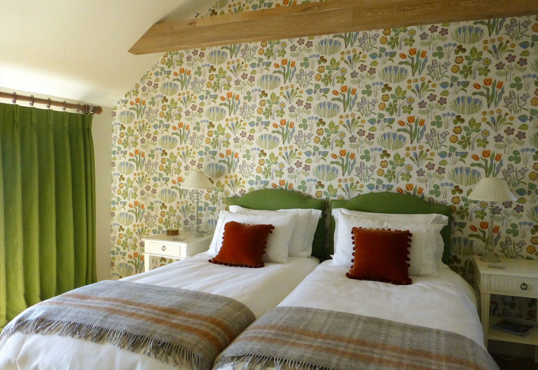 Guest bedroom in home in Orkney with green soft furnishings and patterned wallpaper - part of a project by London interior designer Suzi Searle
